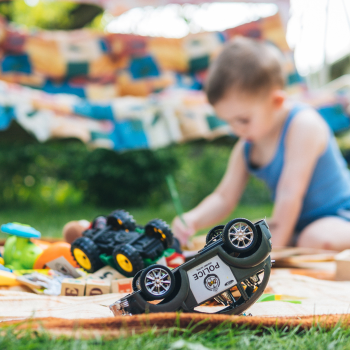 young boy playing in garden with toy cars