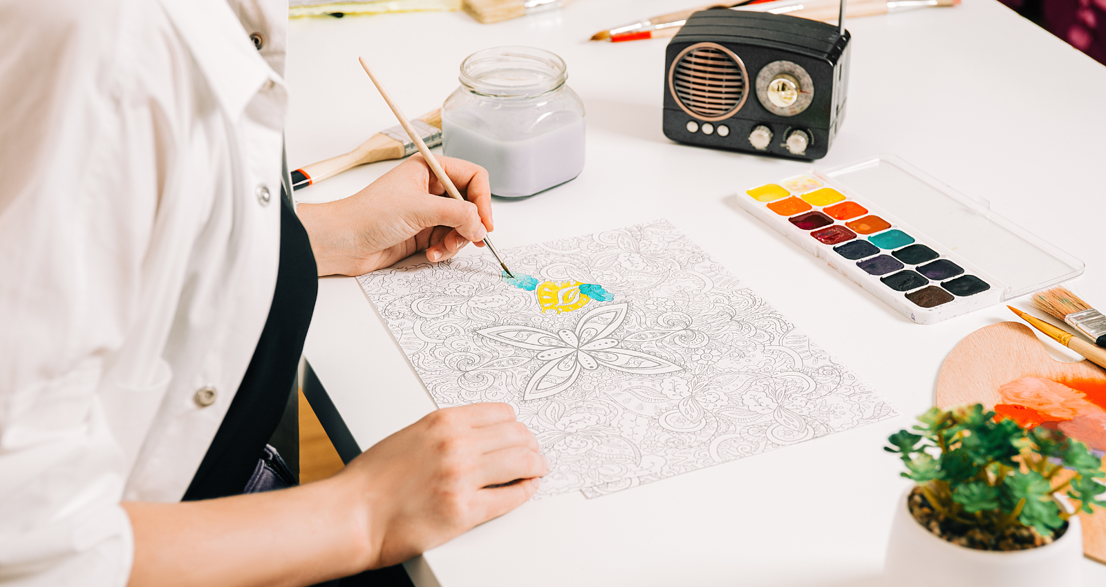 Image of a person painting a mindfulness picture at table 